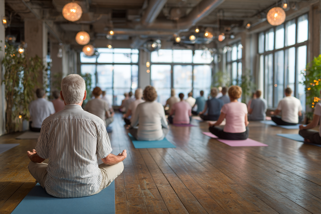 Grup de seniori practicând yoga într-o atmosferă relaxantă și primitoare